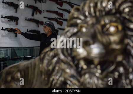 Najaf, Irak. 19 de octubre de 2020. Un cliente inspecciona un fusil de asalto Kalashnikov en una tienda que vende armas de fuego y municiones, donde se permite a las personas comprar armas autorizadas después de emitir los permisos necesarios de las autoridades de seguridad. Crédito: Ameer al Mohammedaw/dpa/Alamy Live News Foto de stock