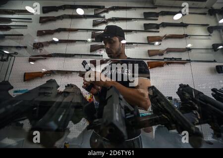 Najaf, Irak. 19 de octubre de 2020. Un traficante de armas demuestra el mecanismo de una pistola en una tienda que vende armas de fuego y municiones, donde se permite a las personas comprar armas autorizadas después de emitir los permisos necesarios de las autoridades de seguridad. Crédito: Ameer al Mohammedaw/dpa/Alamy Live News Foto de stock