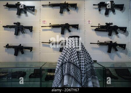 Najaf, Irak. 19 de octubre de 2020. Un cliente observa variantes de rifles de estilo AR-15 colgados en la pared dentro de una tienda que vende armas de fuego y municiones, donde se permite a las personas comprar armas autorizadas después de emitir los permisos necesarios de las autoridades de seguridad. Crédito: Ameer al Mohammedaw/dpa/Alamy Live News Foto de stock