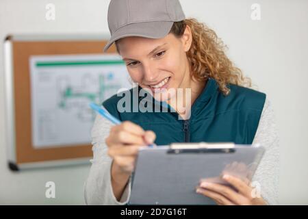 retrato de un alegre empleado de almacén joven haciendo lista de comprobación Foto de stock