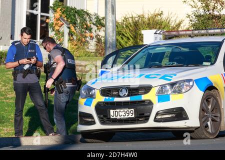 Dos oficiales de policía neozelandeses, uno armado con un rifle de asalto, de pie junto a un coche de patrulla Foto de stock