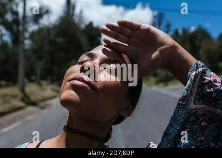 Primer plano de la joven con los ojos cerrados de pie en la carretera durante el día soleado Foto de stock