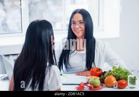 La nutricionista femenina consulta al paciente en el interior de la oficina Foto de stock