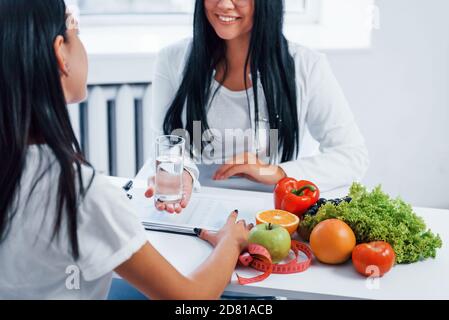 La nutricionista femenina consulta al paciente en el interior de la oficina Foto de stock