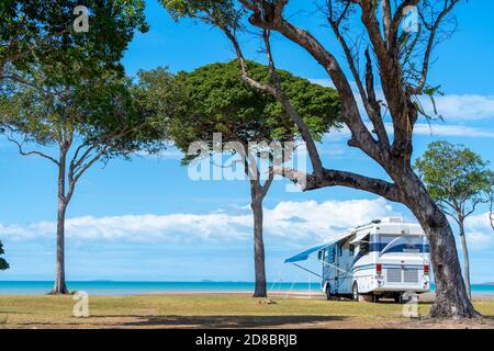 Gran autocaravana estacionada bajo árboles en primera línea de playa, Clairview, Queensland Central, Australia Foto de stock