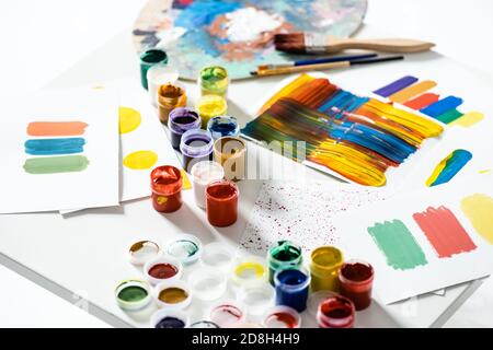 pinturas de gouache, pinceles y pinceladas abstractas coloridas sobre papel sobre fondo blanco