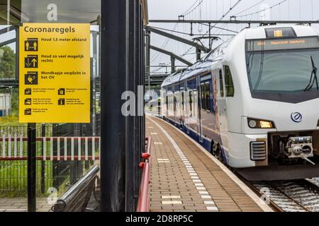 Beek, Limburgo del Sur / países Bajos. 27 de julio de 2020. Estación de tren con un tren y un signo amarillo que indica: Distancia social, caminar a la derecha y t Foto de stock