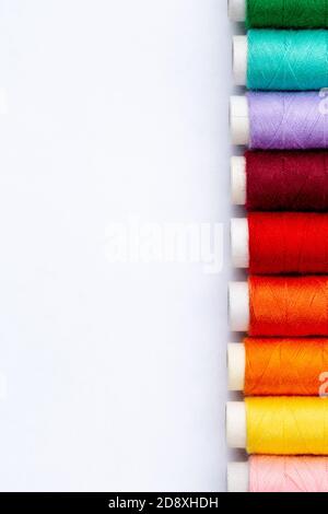Hilos de costura de colores sobre fondo blanco, vista superior. Bobinas de hilo en diferentes colores. Foto de stock