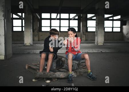 Grupo de adolescentes niños en el interior de un edificio abandonado, fumar cigarrillos. Foto de stock