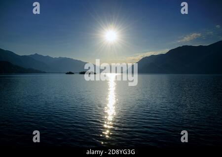 Sunbeam sobre un lago alpino Maggiore con las islas Brissago y la montaña en Ticino, Suiza. Foto de stock