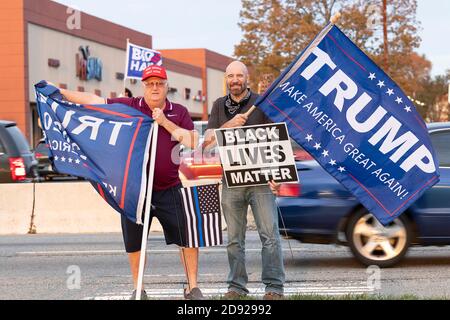 Los partidarios de Donald Trump sostienen señales y banderas en la manifestación local en la acera, incluyendo el signo de "vidas negras importan".