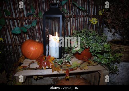 Calle decoración de Halloween con calabazas, macetas de flores, cerca rural y gran vela