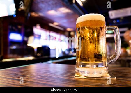 Taza de refrescante cerveza de barril en la mesa con fondo de pub