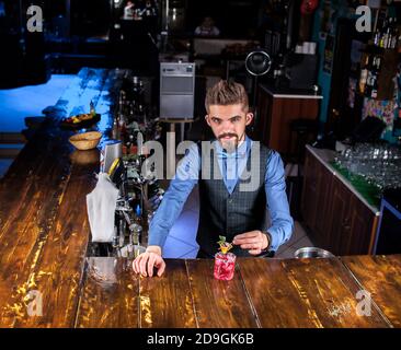 El barman focalizado decora la mezcla de colores en el bar Foto de stock