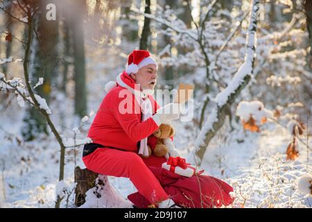 Papá Noel con Regalo y oso de peluche leía la lista de deseos de Navidad.