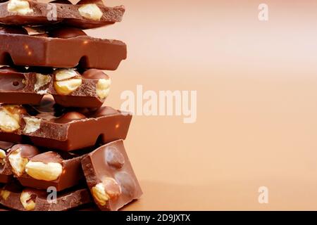 cierre de piezas de chocolate con leche con avellanas sobre fondo marrón con espacio de copia Foto de stock