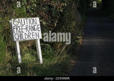 Straiton, Ayrshire, Escocia, Reino Unido, pintado a mano de la señal de la carretera que lee Precaución Free-Range niños. Una serie de señales de advertencia se entregan en forma jocular ingeniosa en un carril de país Foto de stock