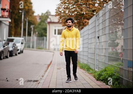 Joven hipster urbano hombre indio en una moderna amarilla. El chico fresco sur de asia usa hoodie caminando la calle de otoño de stock - Alamy