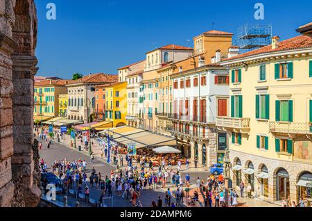 Verona, Italia, 12 de septiembre de 2019: Fila de viejos edificios coloridos y coloridos en la plaza Piazza Bra en el centro histórico de la ciudad, cafés y restaurantes con tiendas y turistas caminando, Región Veneto