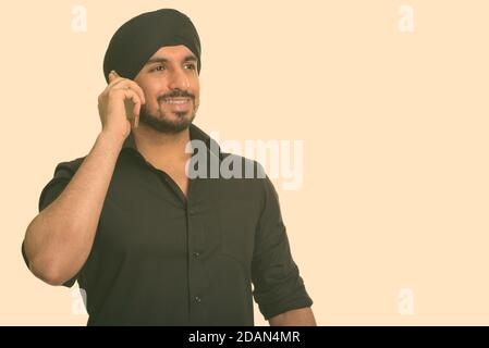 Joven hombre Sikh indio feliz hablando por teléfono móvil Foto de stock