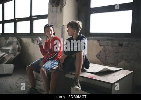 Grupo de adolescentes niños en el interior en edificio abandonado, hablando. Foto de stock