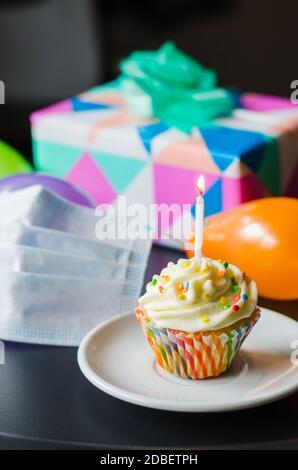 Regeneración Indefinido Gama de Cumpleaños en cuarentena en aislamiento. Cupcake de cumpleaños con vela,  máscara, regalos y accesorios de vacaciones. Distancia social Fotografía de  stock - Alamy