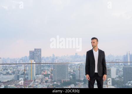 Retrato de un hombre de negocios en la azotea de un rascacielos con copyspace mientras que piensa Foto de stock