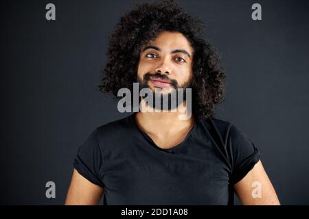 agradable indio árabe masculino en camisa mirando la cámara, tiene un aspecto amigable, abierto de mente tipo aislado sobre fondo negro Foto de stock