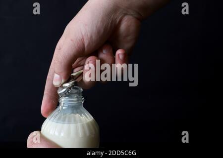 abrir a mano una botella de leche con abrelatas Foto de stock