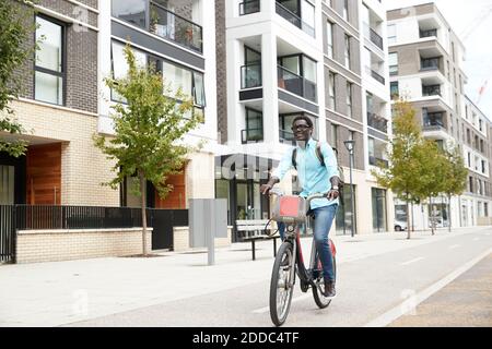 Hombre feliz escuchando música mientras se desplazaba en bicicleta por la ciudad