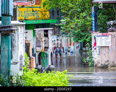 Un hombre desconocido camina por una calle inundada. Las fuertes lluvias del ciclón Nivar han causado inundaciones en Chennai. Foto de stock