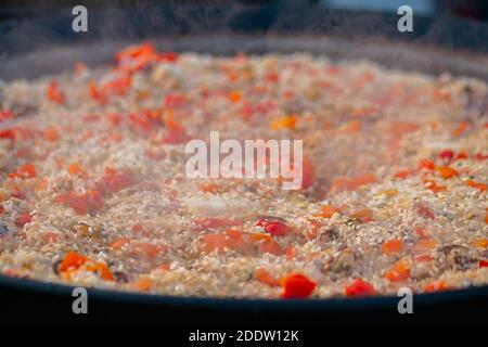 Proceso de cocción de camarones paella, mejillón, arroz, tomate en una sartén enorme - de cerca Foto de stock