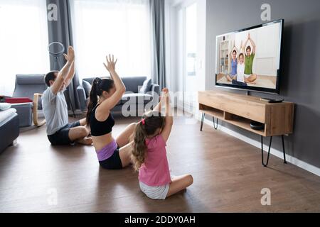 Entrenamiento en casa - mujer haciendo ejercicio viendo un programa de  televisión en pantalla plana programa de fitness yoga ejercicio en la sala  de estar. Yoga niña haciendo ejercicio de meditación en