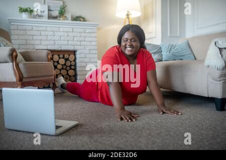 Más tamaño mujer afroamericana sonriendo y de pie en plancha Foto de stock