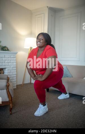 Más tamaño de la mujer afroamericana haciendo lunges Foto de stock