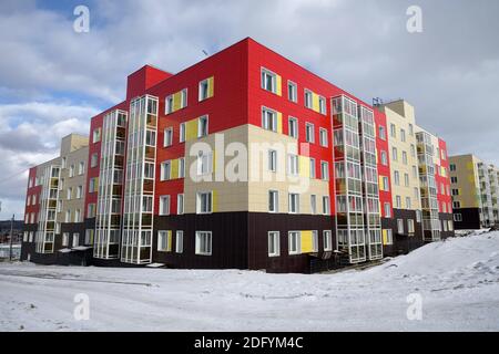 Un nuevo edificio residencial de apartamentos, bellamente bordeado de paneles, con balcones acristalados se encuentra entre los nevados en el pueblo de Taezhny, Kras Foto de stock