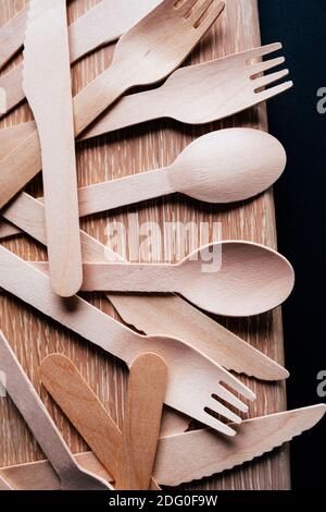 tenedores, cuchillos y cucharas de madera sobre fondo negro Foto de stock