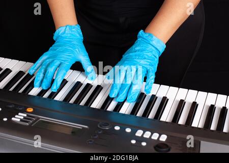 las manos de las mujeres en guantes médicos desechables de goma azul para el virus protección bajo covid-19 aislada sobre fondo negro Foto de stock