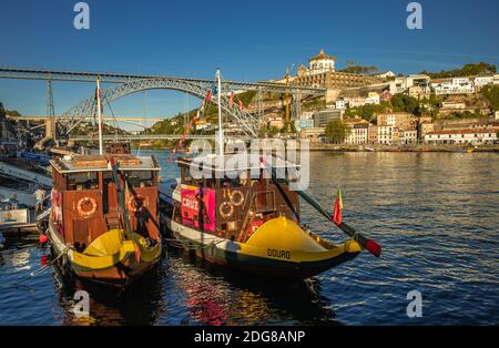 Dos barcos de turismo amarrados cerca de la orilla del río Duero, tomados en Ribeira en Oporto, Portugal. Luís i Bridge está al fondo Foto de stock