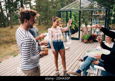 Feliz hombre y mujer amigos criando pan tostado en la terraza de la cabaña Foto de stock
