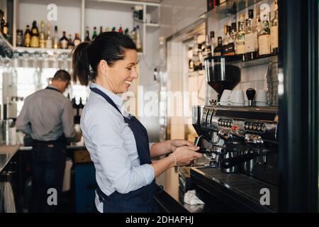 Sonriente barista usando una cafetera en el restaurante Foto de stock