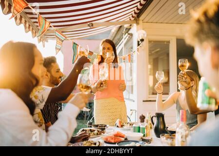 Amigos multiétnicos criando brindis mientras disfrutas en la cena patio Foto de stock
