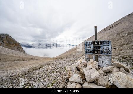 Un camino marcado con un montón de piedras y un signo en el Karwendel, el Breitgrieskarscharte en la cadena Hinterau-Vomper en un estado de humor nublado. Foto de stock