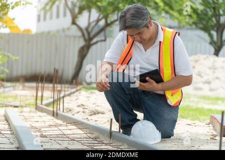 Ingeniería, usar un casco y sosteniendo las tabletas, sentarse a revisar la estructura del corredor en el parque