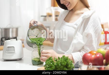 Mujer Asiática cocinando batido de brócoli con una batidora. Estilo de vida comida saludable en la cocina en casa. Vegetariano, concepto de estilo de vida de alimentación limpia.