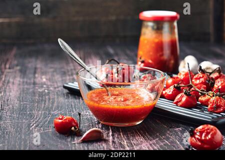 Salsa de tomate e ingredientes sobre un fondo de madera oscura. Foto de stock