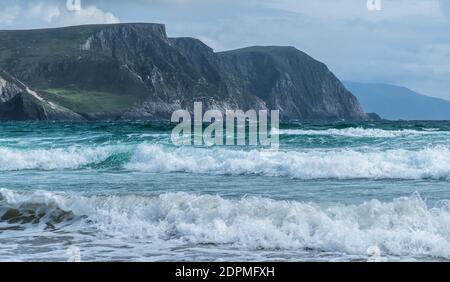 Olas del océano Atlántico con montañas, Keel Beach en la isla Achill, County Mayo en la costa oeste de la República de Irlanda Foto de stock