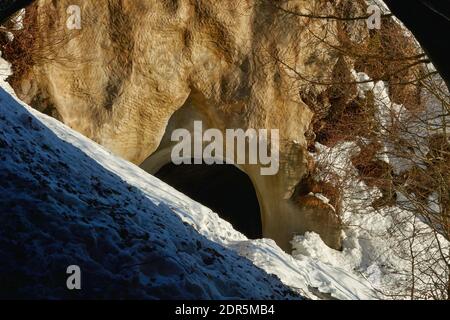 entrada a un túnel de carretera construido en la roca, parcialmente bloqueado por una avalancha de nieve