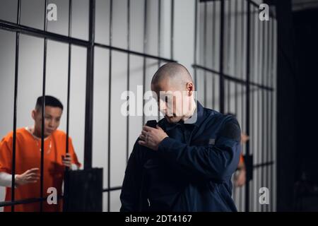 Un supervisor uniformado en una prisión asiática hace un recorrido nocturno por las celdas con prisioneros. Foto de stock