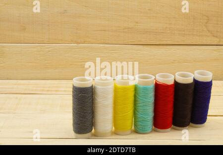 Hilos multicolores para coser con una aguja. Madejas de hilo para coser dispuestas en una fila Foto de stock